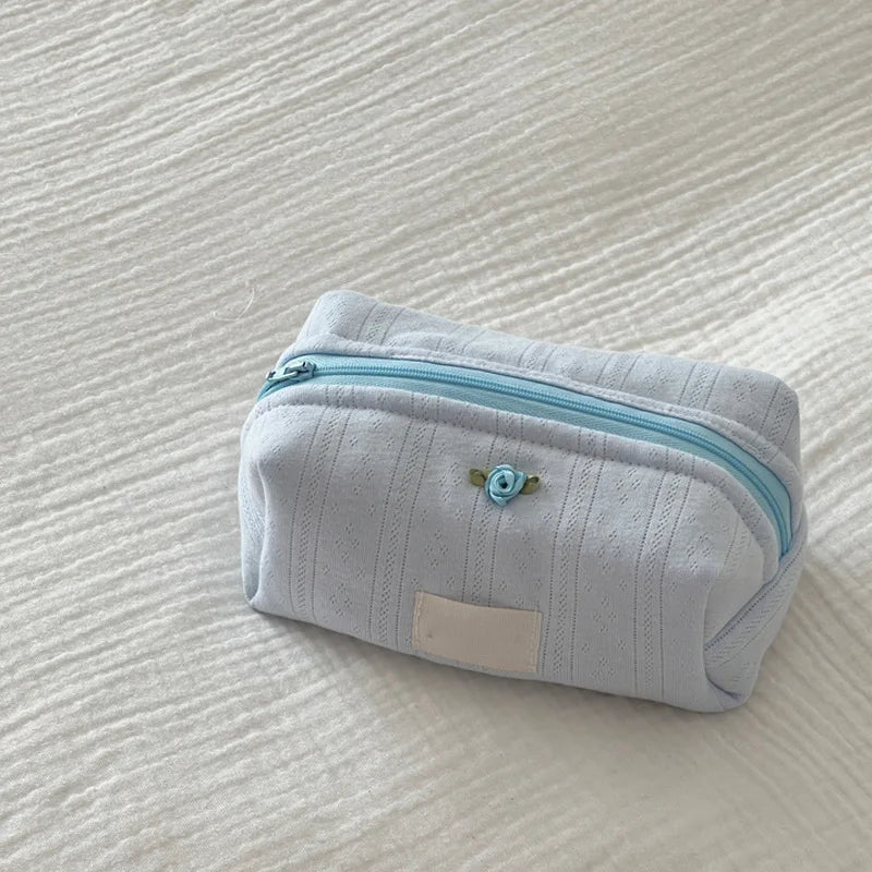 Light blue striped cotton toiletry pouch with a zipper and a small floral embellishment