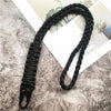 Black hand-woven nylon lanyard with a metal hook lying on a gray textured surface.