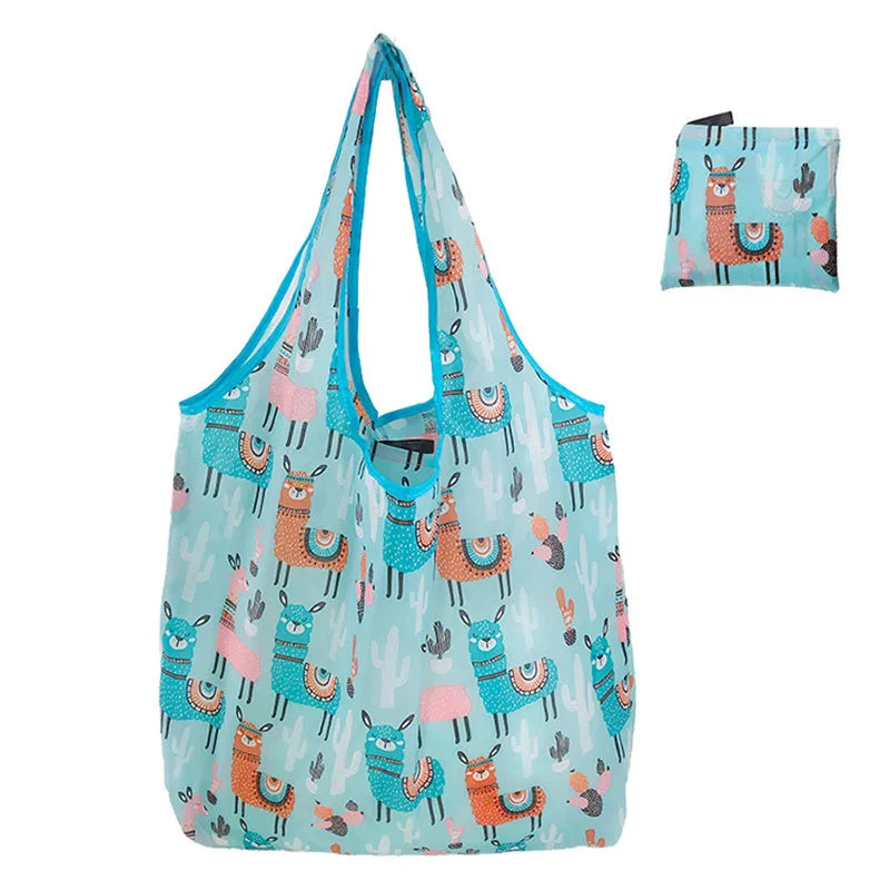 A light blue reusable tote bag featuring a pattern of pink and teal desert animals like camels and cacti.