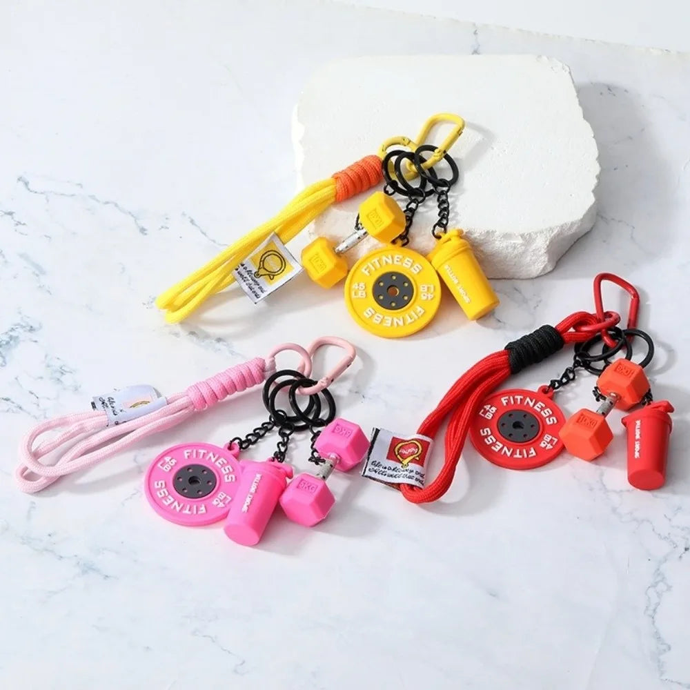 A collection of colorful detachable dumbbell keychain charms and yellow cord accessories displayed on a white marble surface.