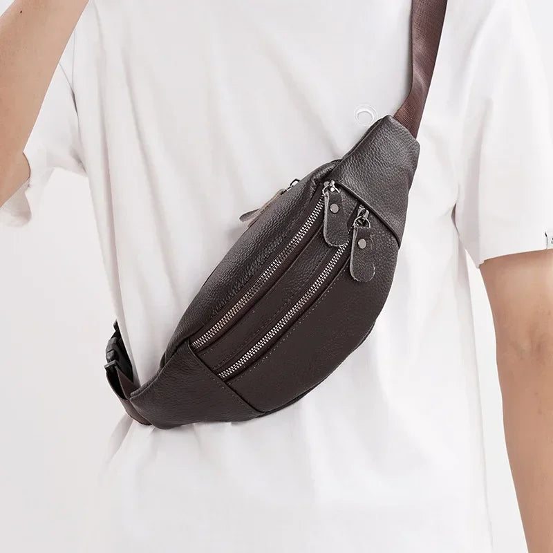 Un bolso cruz de cuero genuino marrón oscuro mostrado contra una camiseta blanca.