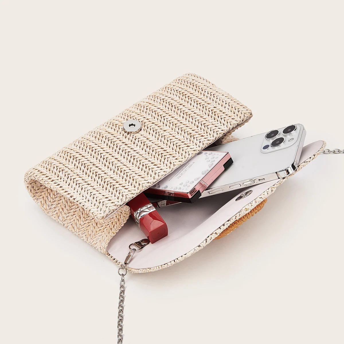 A woven straw envelope clutch with a leather strap and a smartphone inside.