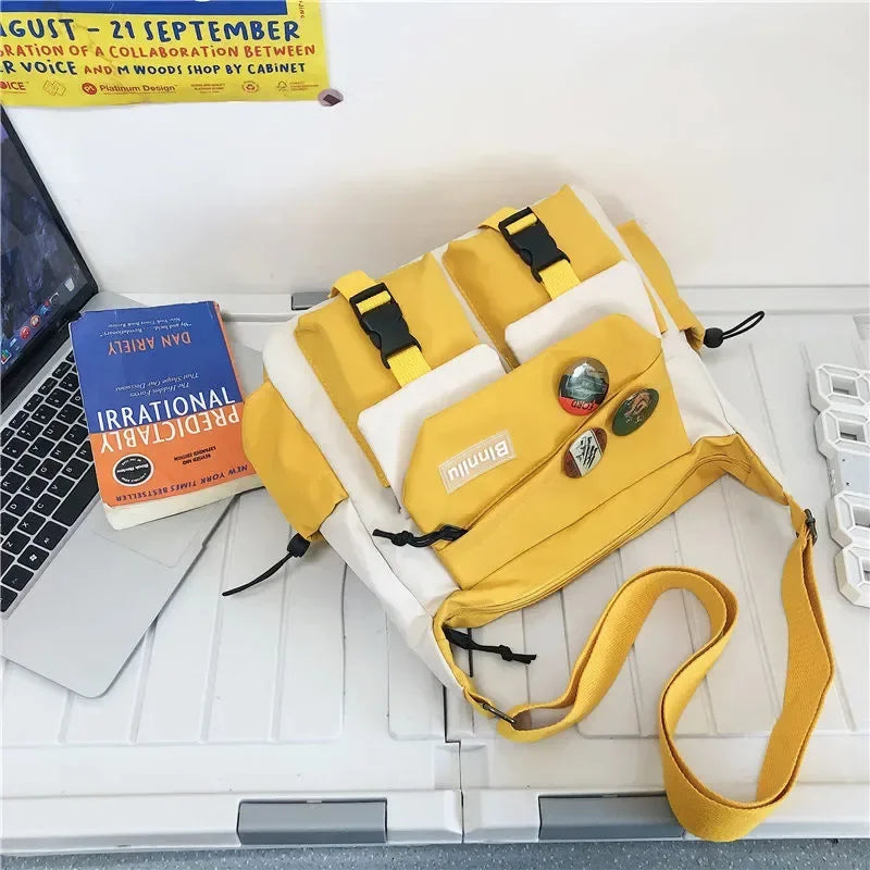 A yellow and white nylon crossbody shoulder bag with black straps is displayed on a white desk.