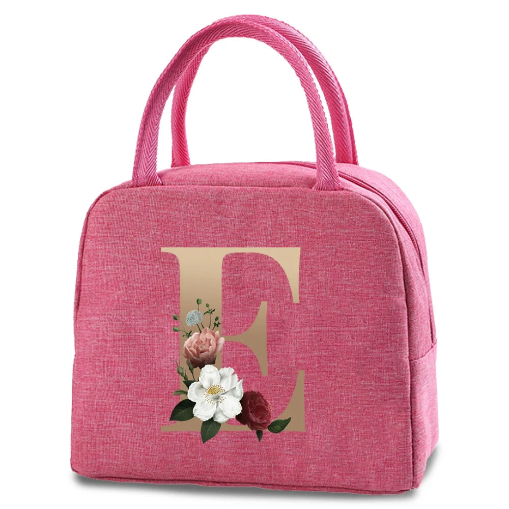 A pink insulated canvas lunch bag featuring a gold letter E and floral accents.