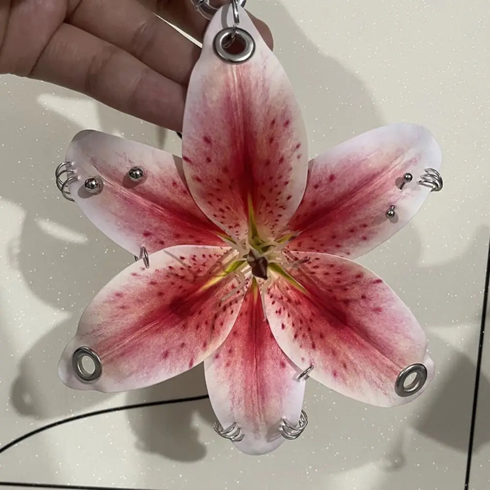 A realistic pink and red orchid flower keychain is being held by a hand.