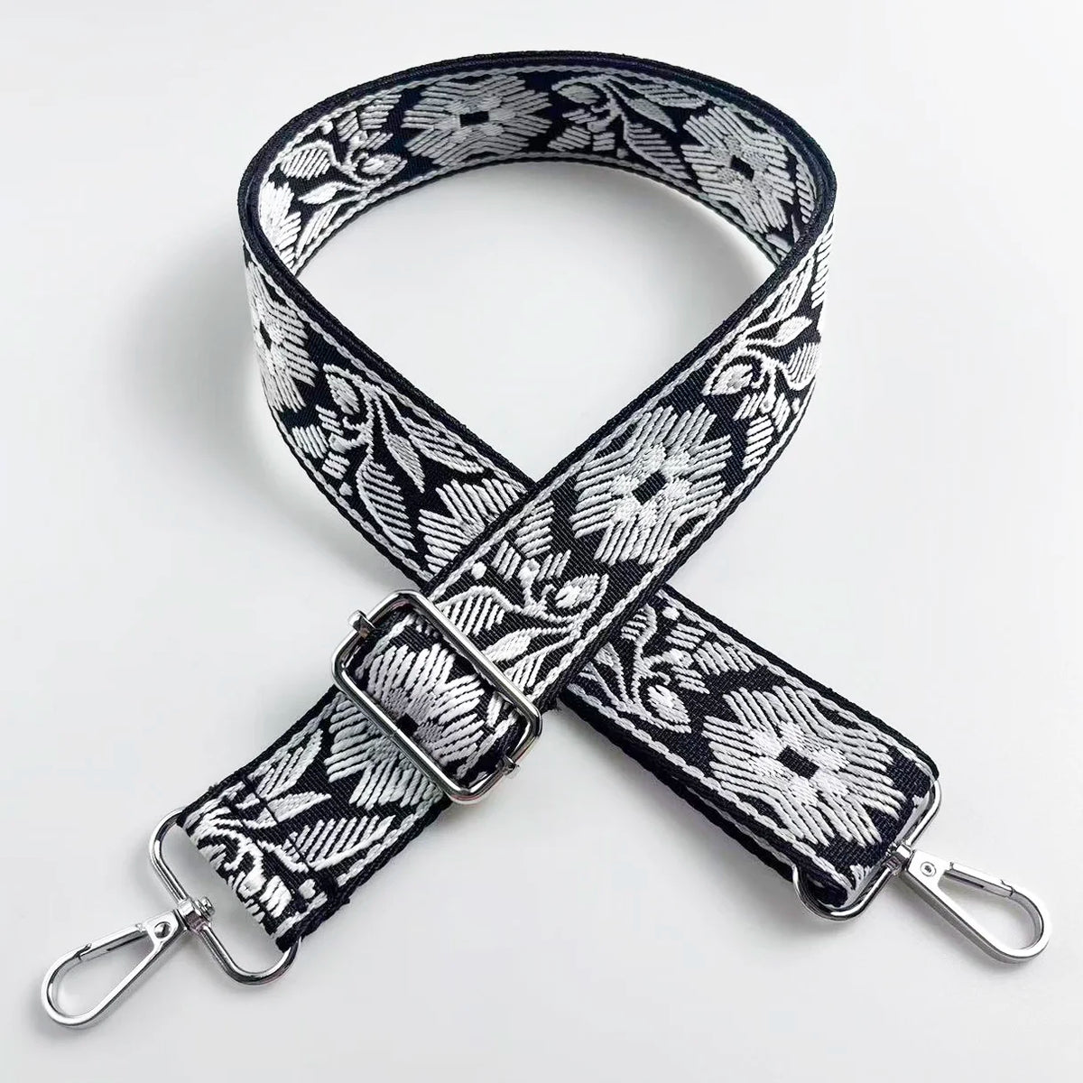 A black and white floral jacquard strap for an adjustable crossbody bag.