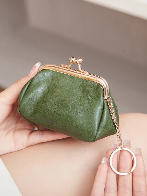 A hand holds a olive green leather coin purse with a gold chain keychain against a neutral background.