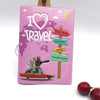 A pink passport cover featuring a 'I love to travel' design with silhouettes of major cities like New York, London, and Paris
