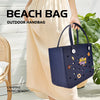 Une femme tient un sac de plage en caoutchouc EVA bleu foncé contre un fond en bois blanc.