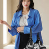 A woman models a blue denim shirt and black pants while holding a black and white patterned PU leather tote bag.