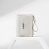 A white PU leather mini wallet with a silver pendant is shown resting on a white surface.
