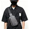 A person wearing a black shirt and face mask is holding a gray chest bag.