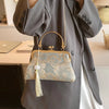 A light blue embroidered silk evening clutch with a gold chain strap is displayed against a gray coat.