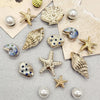 A collection of gold and silver conch shell shoe charms, including starfish, pearls, and various decorative shapes.