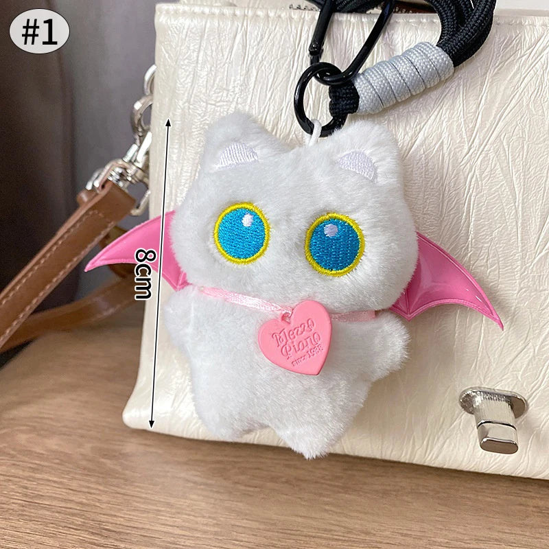 Colgante de gato blanco de peluche con acentos rosados, mostrado en un bolso claro.