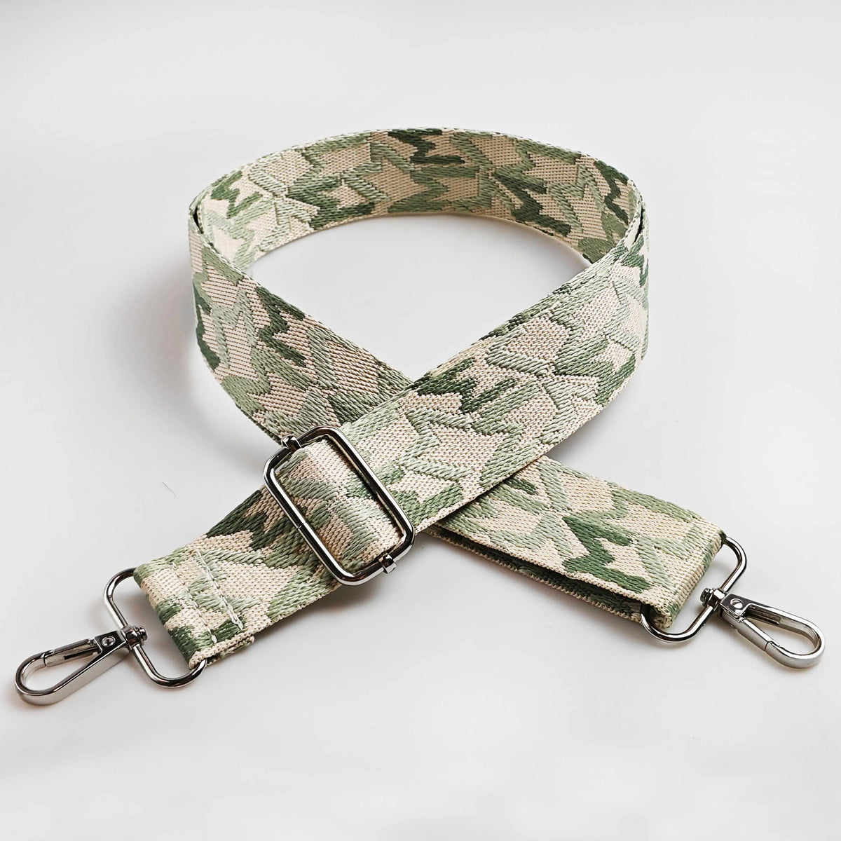 A beige and green jacquard patterned strap for an adjustable wide crossbody bag.