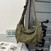 A olive green cotton canvas shoulder crossbody bag hanging on a metal grid.