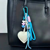 A handmade PU leather heart keychain with braided blue and pink rope attached to a black bag.