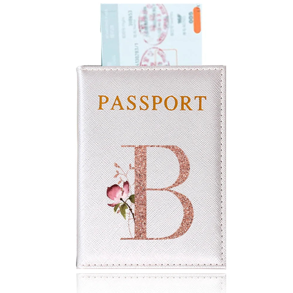 A pink leather passport holder featuring a gold embossed letter B and a floral design.