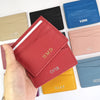 Une main tient plusieurs porte-cartes en cuir véritable et gravés sur mesure, dans diverses couleurs et finitions.