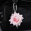 A realistic pink orchid flower keychain attached to a black leather handbag.