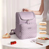 A purple insulated travel backpack is shown on a table next to food items, highlighting its insulation and preservation featu