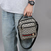 A man wearing jeans and a gray shirt holds a patterned black and gray crossbody sling bag.