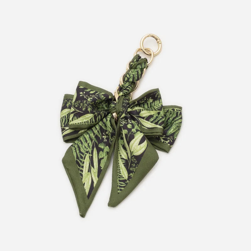 A dark olive green patterned fabric bow with a gold chain strap extension for a handbag.