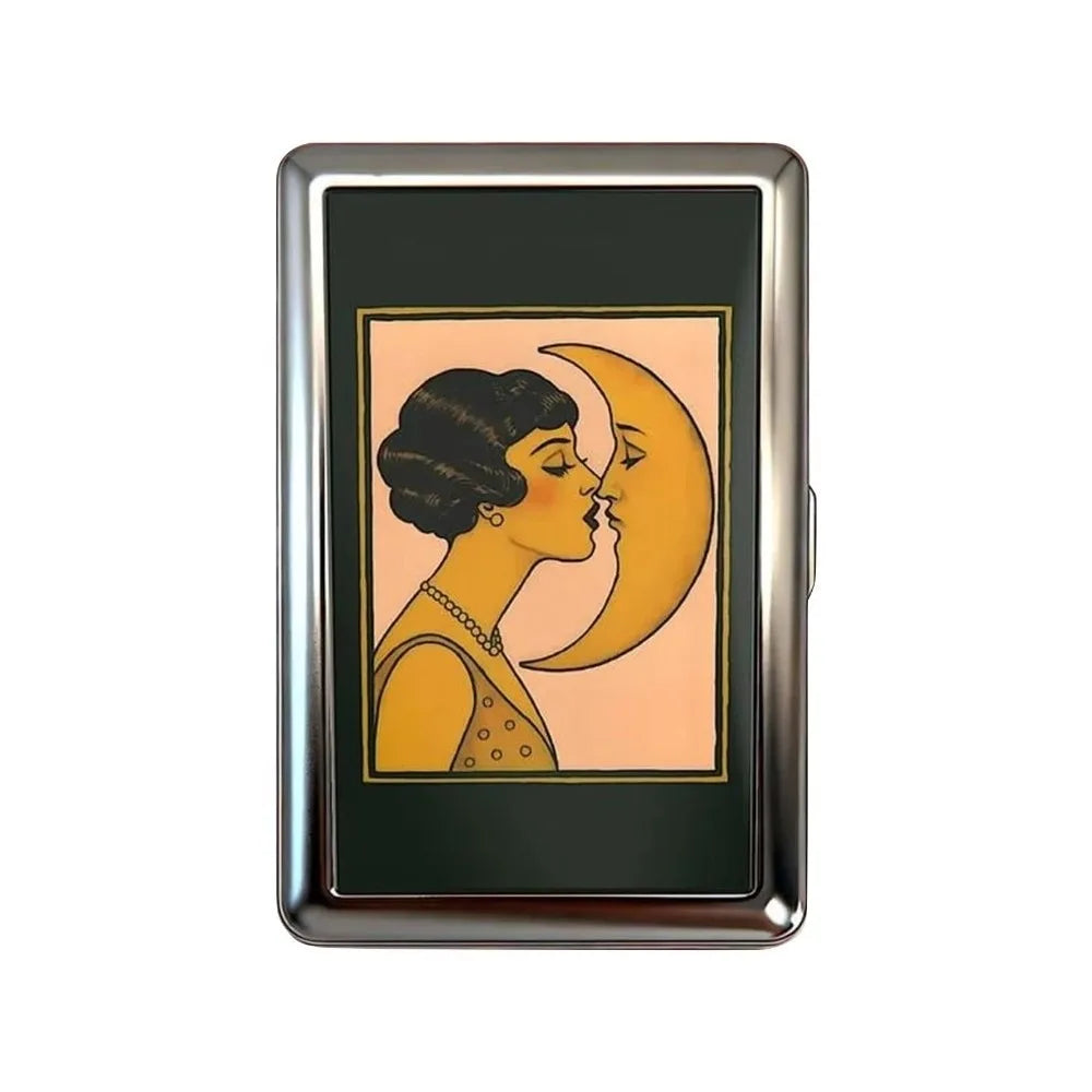 A vintage snap metal card holder featuring a gold-toned illustration of two profiles kissing against a peach background.