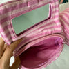 A pink and white striped makeup bag with a flip-top mirror is shown being held open.