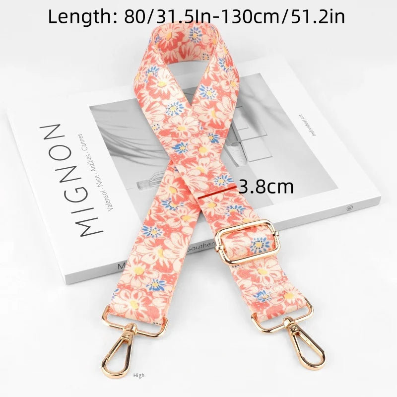 An adjustable diagonal shoulder strap in coral floral print shown on a white box.