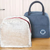 A light silver insulated lunch bag next to a dark blue fabric lunch bag on a wooden surface.