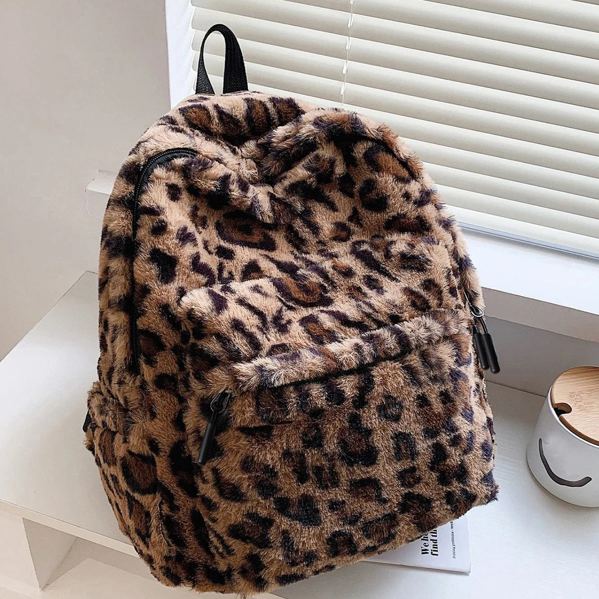 A brown and black leopard print plush backpack with multiple pockets resting on a white surface.