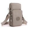 A light beige compact nylon crossbody phone bag with a leather strap and circular emblem.