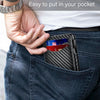 A hand places a black carbon fiber slim wallet into the pocket of dark blue jeans.