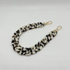 A close-up of a black and white patterned acrylic chain bracelet.