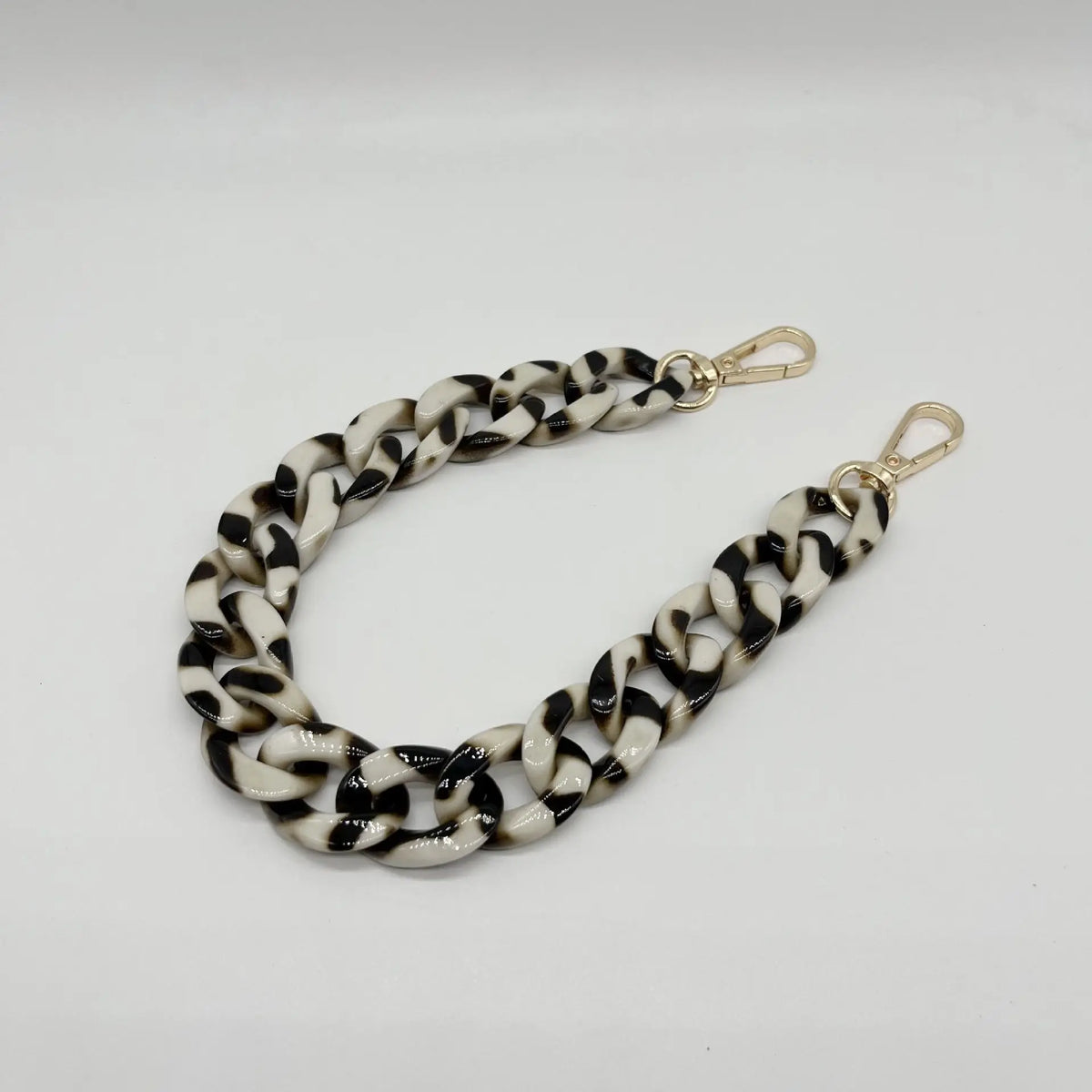 A close-up of a black and white patterned acrylic chain bracelet.