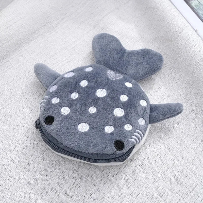 A gray shark mini plush coin purse wallet with white polka dots resting on a light fabric background.