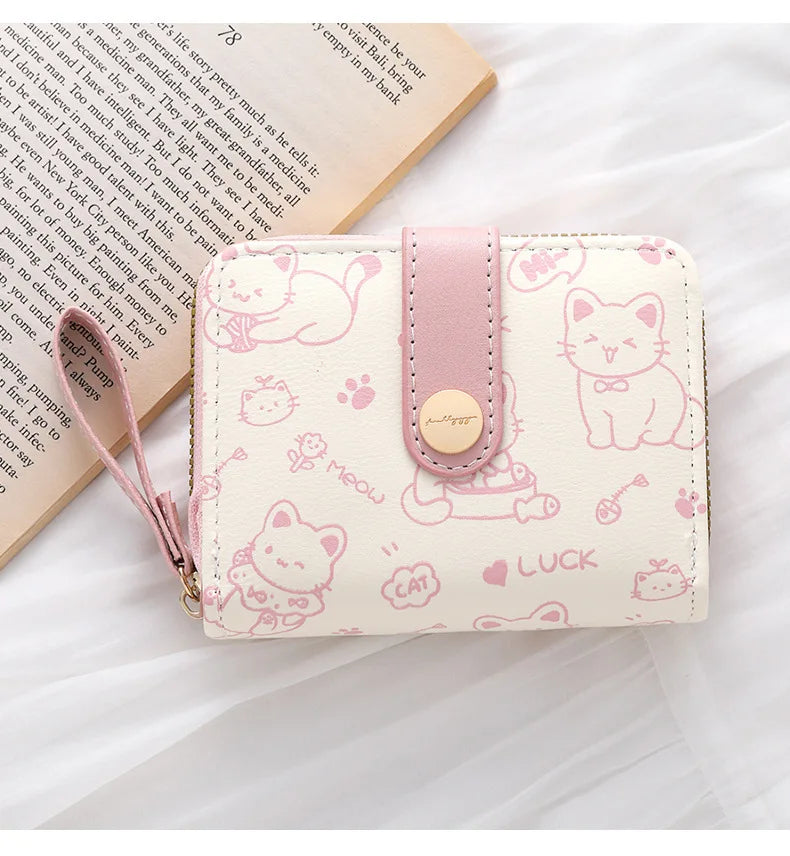 Hellrosa Leder-Portemonnaie aus Kunstleder mit süßen Katzenillustrationen und rosa Trageriemchen.