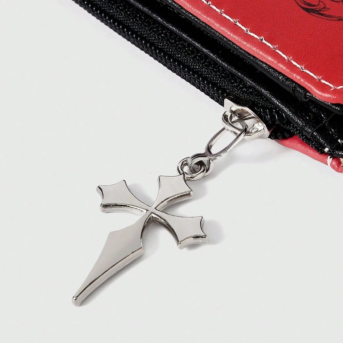 Silver gothic cross pendant attached to a black and red leather wallet with a zipper.