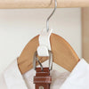 A multi-hook wardrobe organizer with a white plastic hanger and a brown leather strap hanging from it.