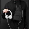 A person wearing a black shirt holds a white wireless headphone and a black nylon crossbody sling bag.