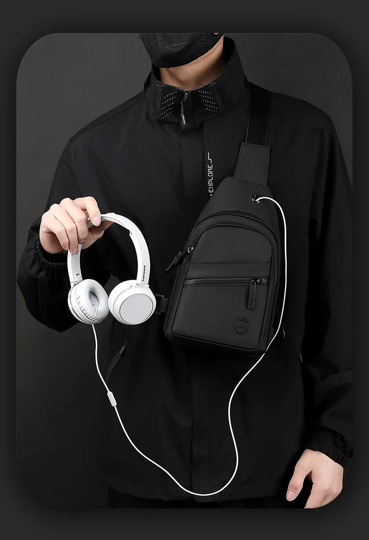 A person wearing a black shirt holds a white wireless headphone and a black nylon crossbody sling bag.