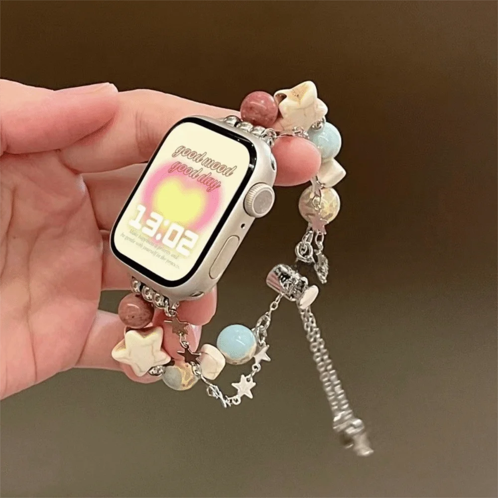 Eine Hand hält ein verstellbares Metallarmband mit verschiedenen Kristallperlen und einem Smartphone angebracht.