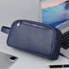 Pochette de soirée en cuir PU bleu marine avec fermeture éclair et sangle posée sur un ordinateur portable argenté.