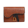 Porte-cartes clutch crocodile marron avec initiale D dorée et sangle noire.