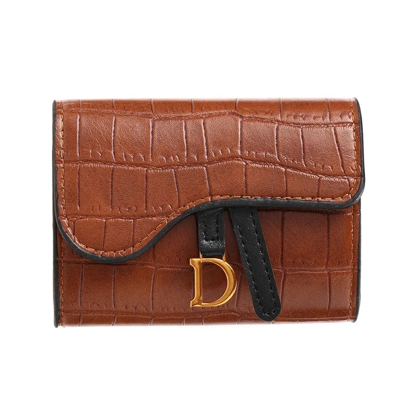 Porte-cartes clutch crocodile marron avec initiale D dorée et sangle noire.