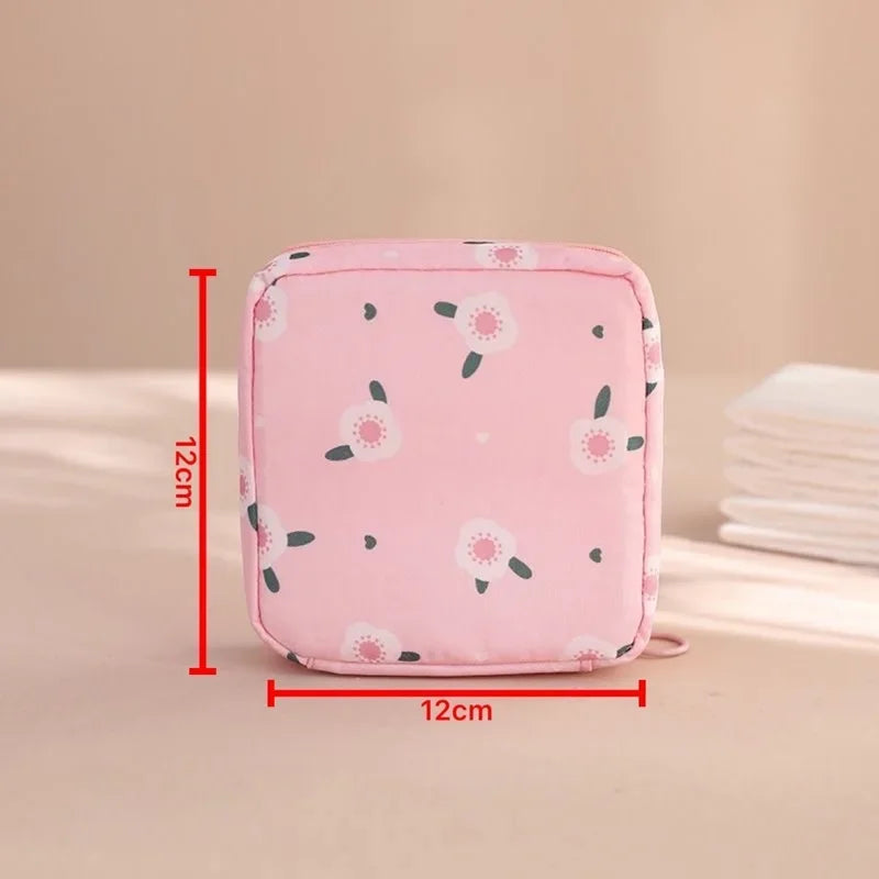 Pink compact sanitary pad storage pouch with a floral pattern shown on a light surface.
