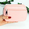 A hand holds a pink compact PU leather mini wallet with a silver keychain against a white background.
