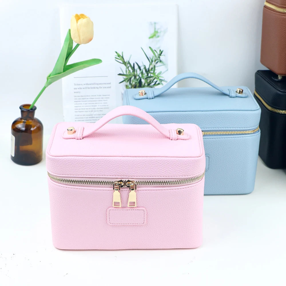 A pink customizable PU leather makeup bag with a light blue accent, sitting next to a yellow tulip and a dark leather pouch.